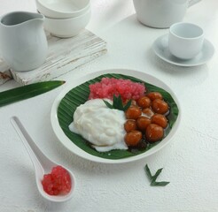 a bowl of sweet porridge and starch balls with brown sugar sauce and coconut milk