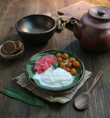 serving of a bowl of sweet porridge and starch balls against a background of clay cookware