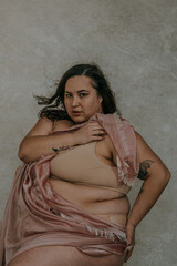 Naklejka premium close-up plus size metis woman looking at camera holding pink fabric wearing nude bra looking at camera