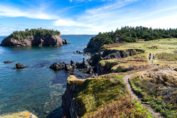 Two children running on a hiking trail along the East Coast of Canada overlooking the Atlantic Ocean at Chance Cove Newfoundland.