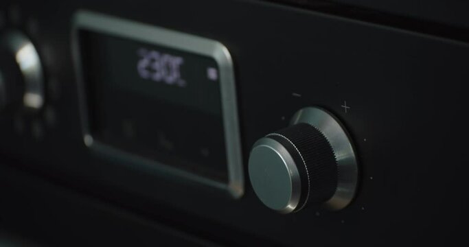Person hand rising temperature of oven using knob, close up view