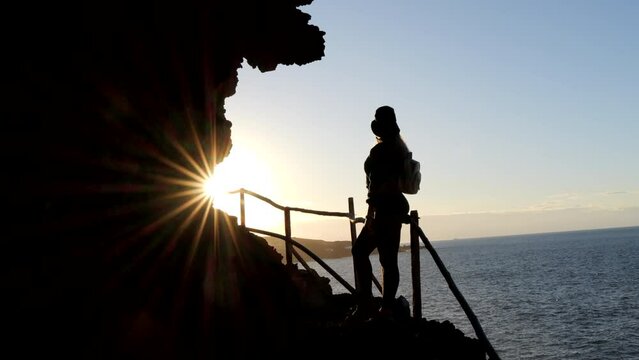 young woman with hat admires during sunset, the landscape found on the coast of the municipality of Galdar on the island of Gran Canaria and during sunset.