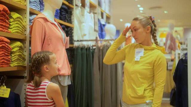Happy mother and daughter choose looking for clothes in shopping mall. Mother and daughter shopper customer is looking and buying casual clothes in clothing store. Concept shopping clothes store