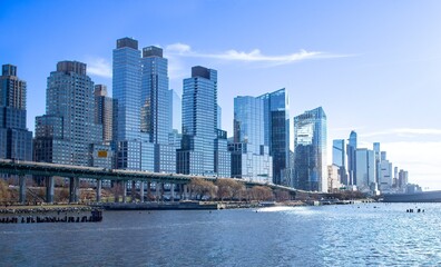 Buildings along Henry Hudson Parkway and West Side Highway, Manhattan, New York City, on a sunny winter day. Hudson River in foreground.