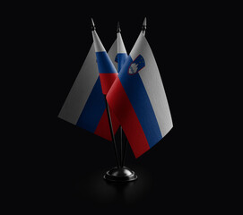 Small national flags of the Slovenia on a black background