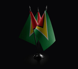 Small national flags of the Guyana on a black background