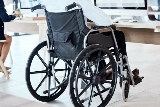 Wheelchair, office and business man disability in the workplace doing administrative assistant work. Working, computer and desk job of a worker back with technology in a coworking space with staff