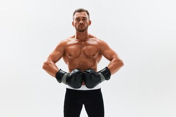 Fototapeta premium Man athletic bodybuilder poses in boxing gloves with nude torso abs in full-length background, boxing and martial arts. Advertising, sports, active lifestyle, competition, challenge concept. 
