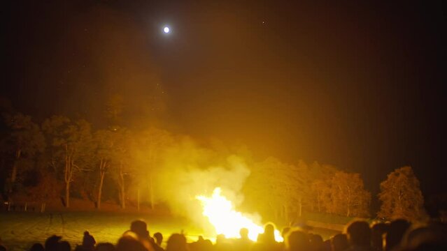 People gathered around fire in the dark during a full moon