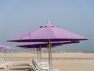 Purple beach umbrellas. Blue sky. Relaxing context. Summer holidays at the sea. General contest and location