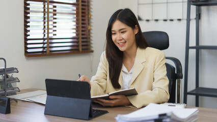 Work of secretary concept, Female secretary pointing data on tablet and taking notes in notebook