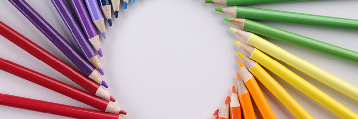 Colored pencils in acircle closeup. Colored pencils lie around on a white background