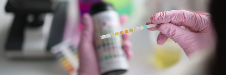 Chemist in laboratory checks ph strips closeup