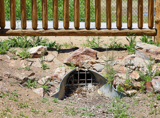 A culvert with grate or trash rack to prevent debris from entering.