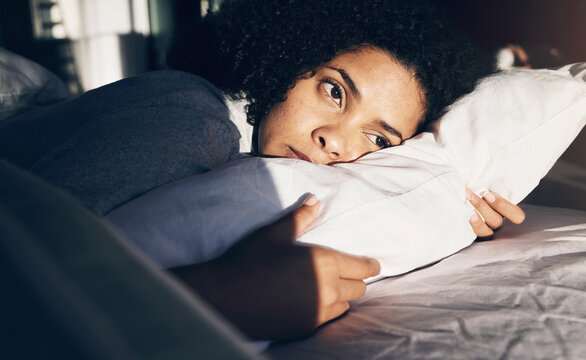Anxiety, depression and sad woman tired in bed with insomnia, thinking and trying to sleep while sick. Morning, sunrise and depressed girl with stress, mental health problem and fatigue in bedroom