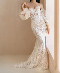 Beautiful bride with the naked shoulders dressed in the white long wedding dress. Silhouetted classical wedding dress with wide collapsible sleeves and gorgeous floral lace