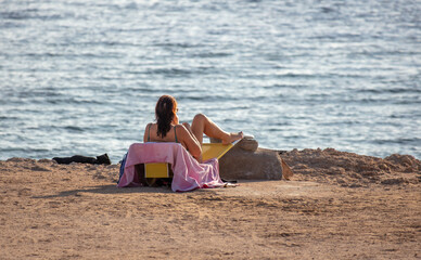 Fototapeta na wymiar Girl in a bathing suit on a beach chair by the sea.