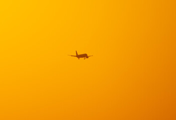Silhouette of an airplane coming in for landing at sunset.