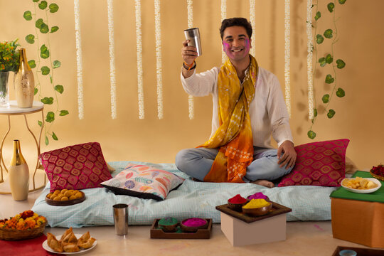 A young man is drinking a glass of bhang on holi festival