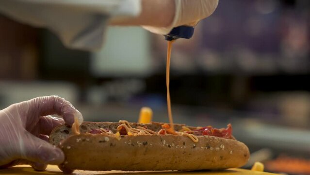 Chipotle sauce being poured over a sandwich bread roll in a deli slow motion shot