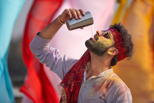 A young man cheerfully drinking bhang during holi celebrations