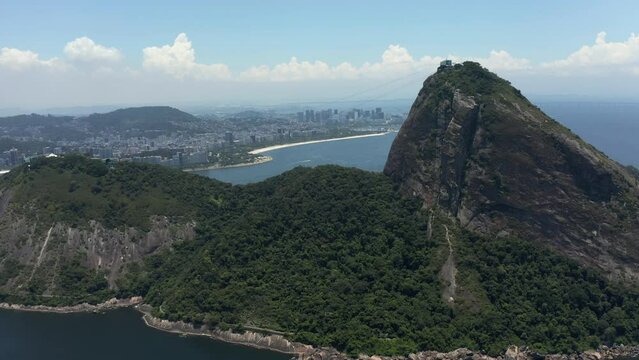 Sugarloaf Mountain with Rio de Janeiro downtown skyline. Flying backwards, sunny day, midday