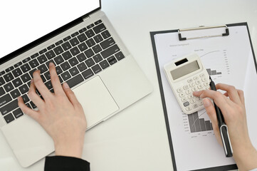 Top view of a female accountant or businesswoman using laptop and calculator, working at her desk.