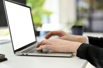 Side view image of a businesswoman typing on laptop keyboard, using laptop at her office desk.