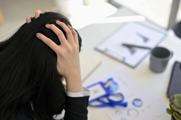 Stressed and furious Asian businesswoman sits at her office desk, suffering from hard working.