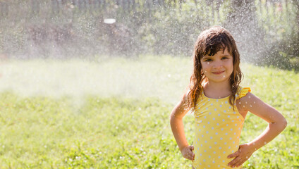 Naklejka na ściany i meble Happy child girl in a bathing suit playing with garden hose and having fun with spray of water in sunny backyard. Summer time. Enjoying the little things. Summer holiday. banner