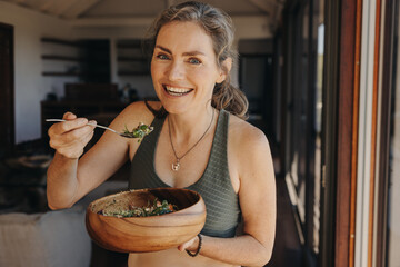 Happy vegan woman eating a vegetable salad from a bowl