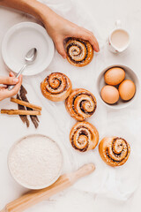 hands of woman making cinnamon rolls at table, recipe ingredients 