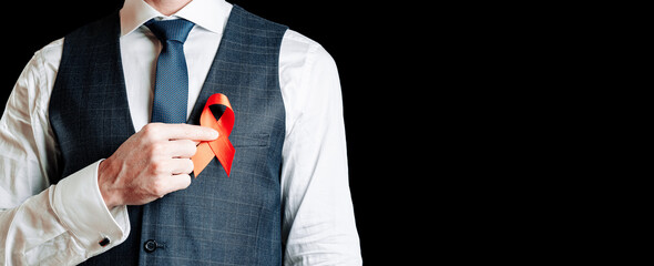 Aid ribbon silk. Red ribbon in hiv world day in man hand. Awareness aids and cancer symbol on black background. HIV, AIDS and aging awareness month with copy space.
