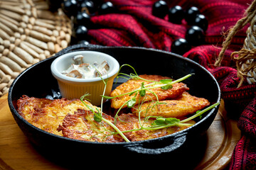 Traditional Ukrainian deruny with meat in a black pan. Ukrainian cuisine Potato pancake. Close up