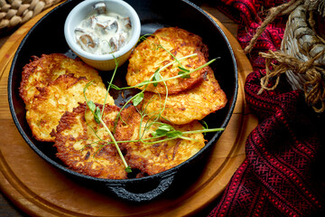 Traditional Ukrainian deruny with meat in a black pan. Ukrainian cuisine Potato pancake. Close up