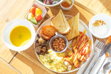 Traditional english or american breakfast consisting of scrambled eggs, sausages, beans and bread top view on wooden table.