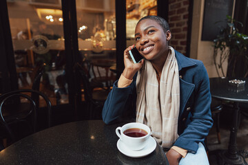 Happy african woman in cafe talking on the phone