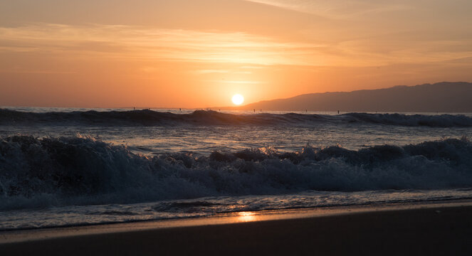 California sunset over pacific ocean waves with Malibu in the distance
