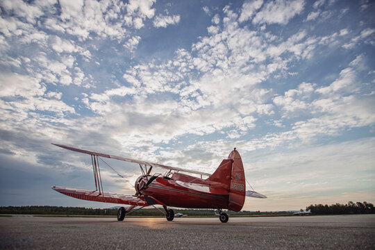 Vintage red Waco airplane sits on runway at sunrise in Maine