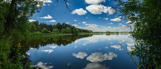 Lake in the forest with sky and clouds reflection