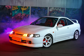 90s sport car with smoke in neon light on the asphalt road at night