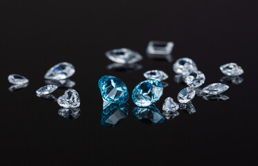 Blue and white polished diamonds of various cuts and sizes on black background. High quality photo