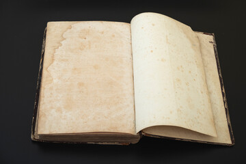 Top view of an old open book with blank pages on a dark background as copy space, retro toned image.
Open book on dark background