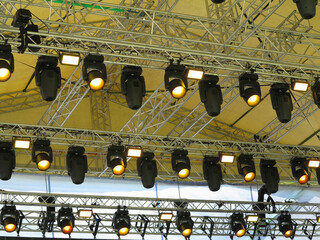 Spotlight devices in a row on  rigging steel trusses, installation of professional stage equipment.