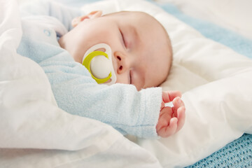 Cute three month old baby sleeping in comfortable bed.