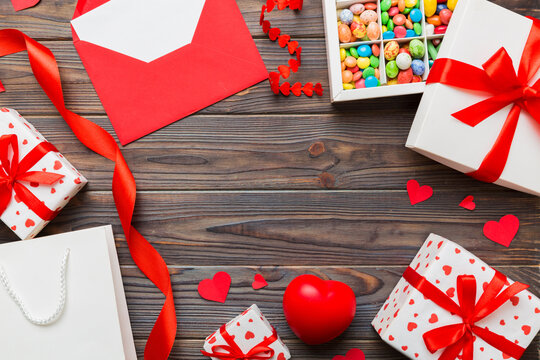 top view photo of st valentine day decor shopping, bag, envelope, gift, box, candy and red heart on colored background with empty space. Frame background