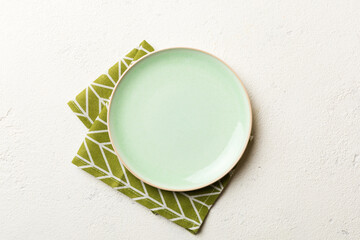 Top view on colored background empty round green plate on tablecloth for food. Empty dish on napkin...