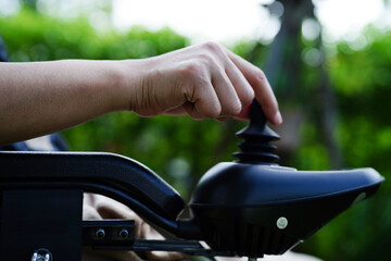 Asian elderly woman disability patient sitting on electric wheelchair in park, medical concept.