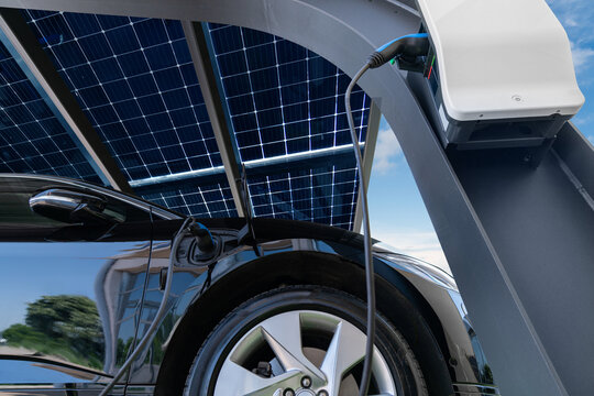 Electric car is charged from a charging station that takes energy from solar panels. Close up	