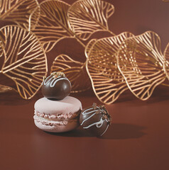 Dessert Decadence: Chocolate Bon-Bons and a Pink French Macaron Cookie with Gold Ginkgo Biloba Leaves in the Background